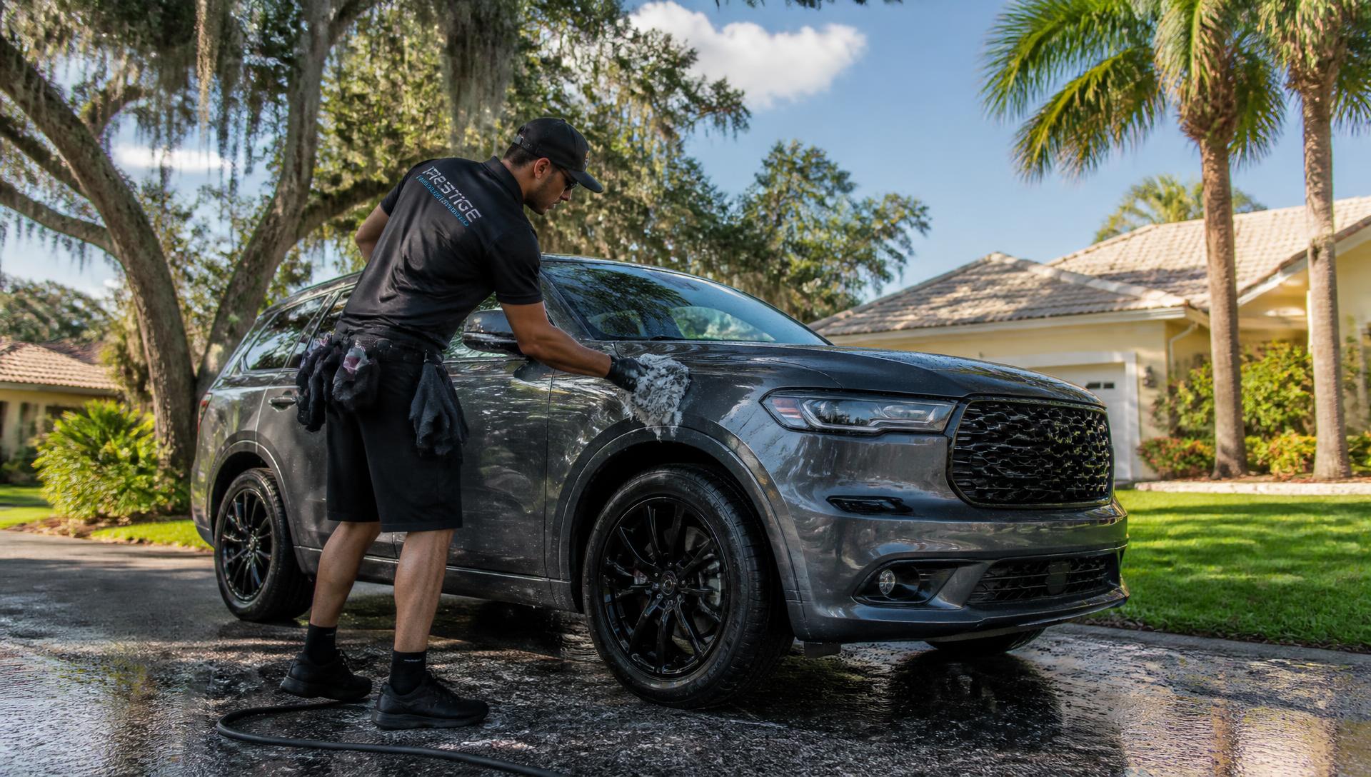 Detailer hand washing an SUV in a Jacksonville driveway